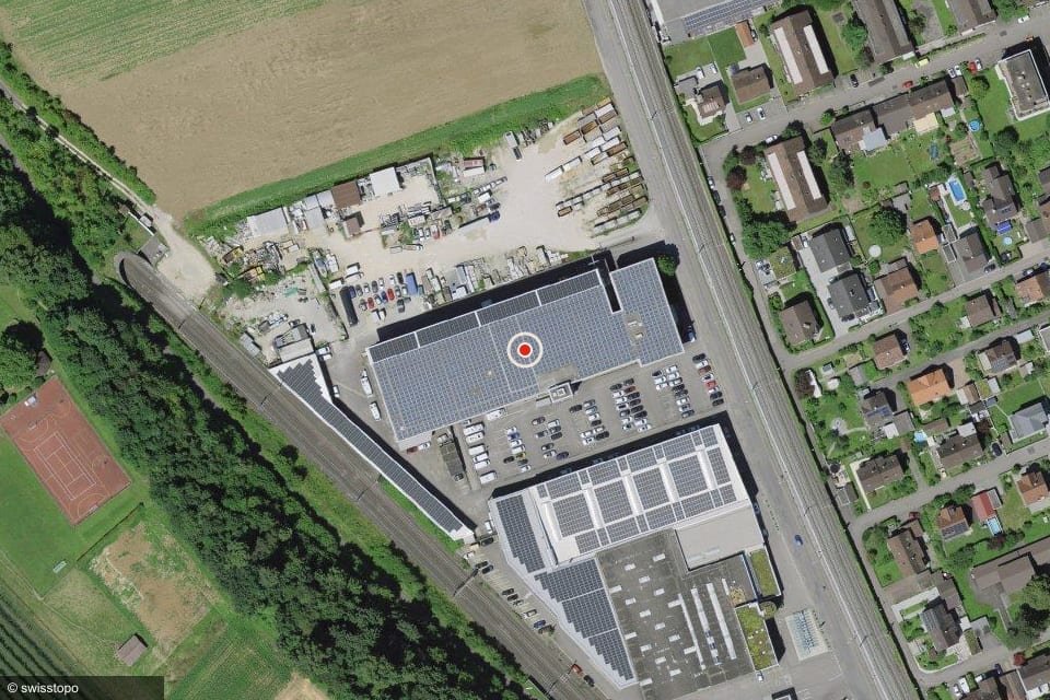 Luftbild Industriestrasse 17, 4410 Liestal: das Laua-Gebäude mit dem Parkplatz an der Südostseite, Bahnlinie und Industriestrasse westlich davon.